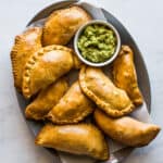 Beef empanadas on a plate served with a side of guacamole.