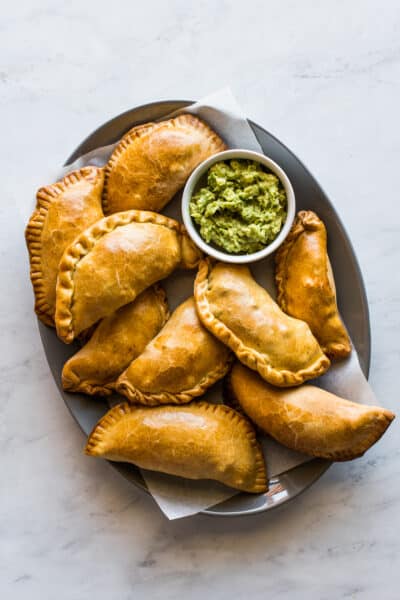Beef empanadas on a plate served with a side of guacamole.