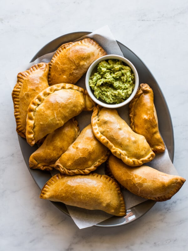 Beef empanadas on a plate served with a side of guacamole.