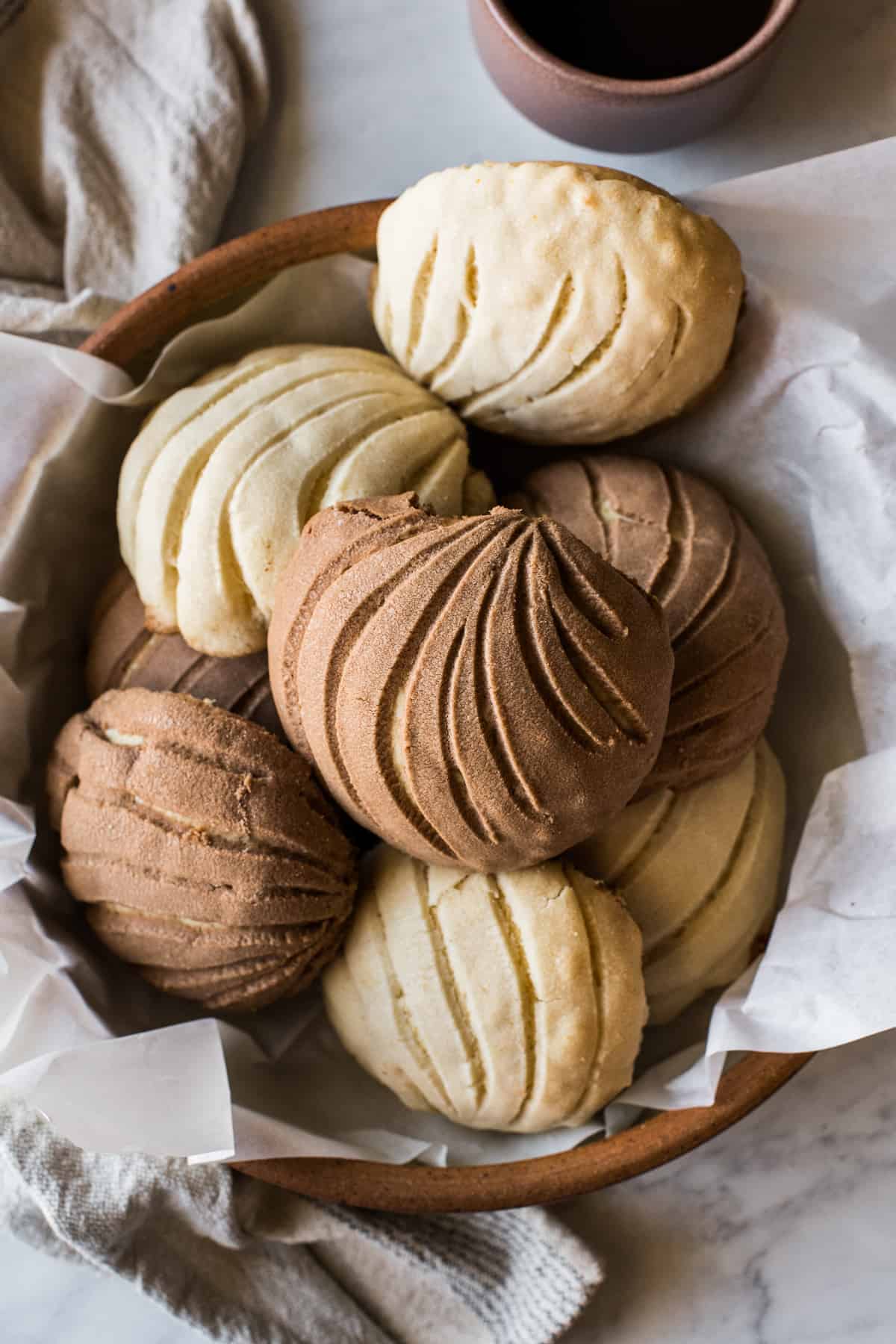 Baked conchas with brown chocolate topping and white chocolate topping in a large serving bowl ready to eat.