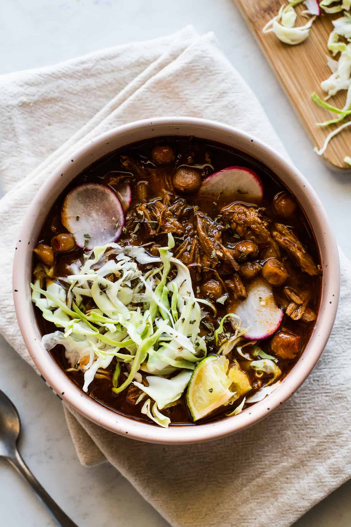 Instant Pot Pozole in a bowl topped with shredded cabbage, sliced radishes, and Mexican oregano.