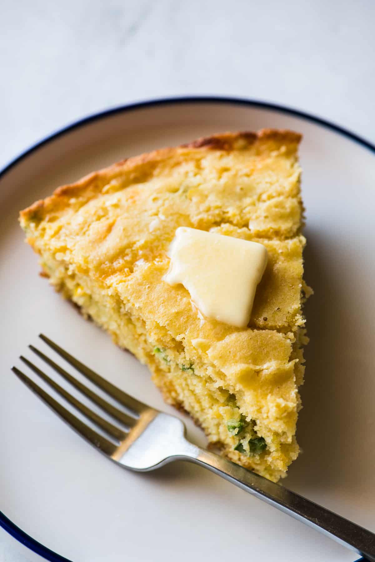 A slice of Jalapeño Cornbread with a pat of melted butter on top.