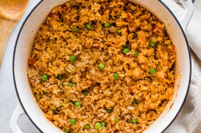 Cooked Mexican rice in a pot with peas mixed in.