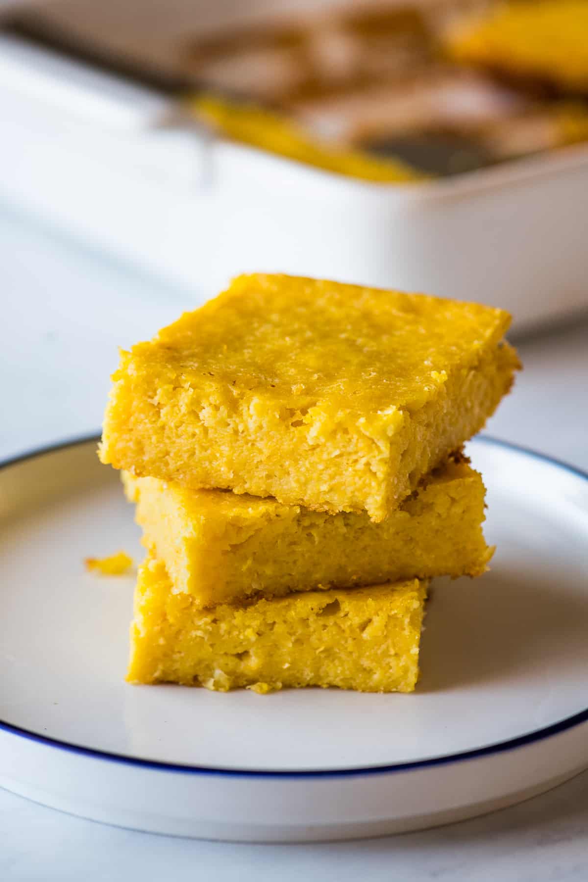 Three slices of Pan de Elote stacked on top of one another on a plate.