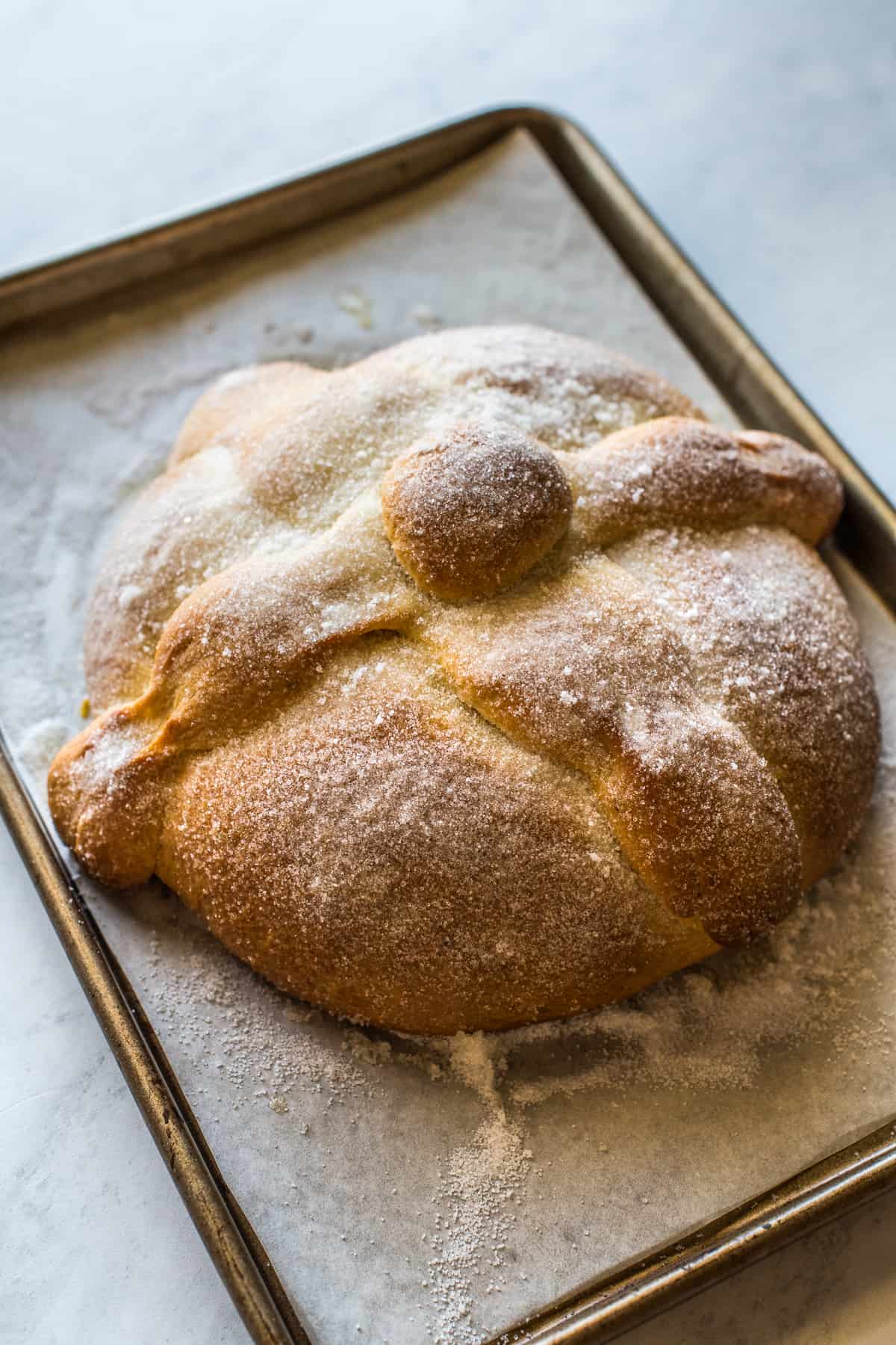 Pan de Muerto (or Day of the Dead Bread) on a baking sheet ready to eat.