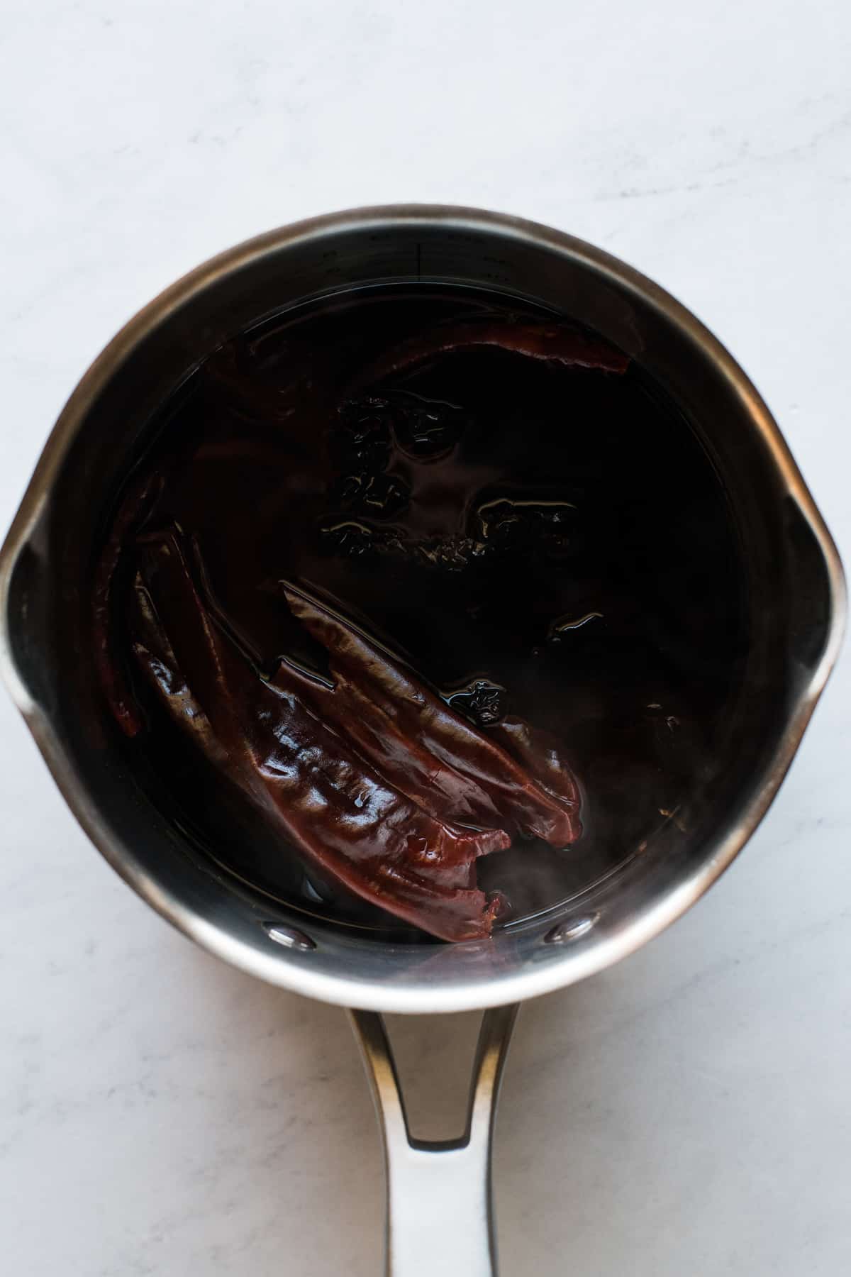 Dried chiles soaking in a pot of hot water for making a pozole recipe.