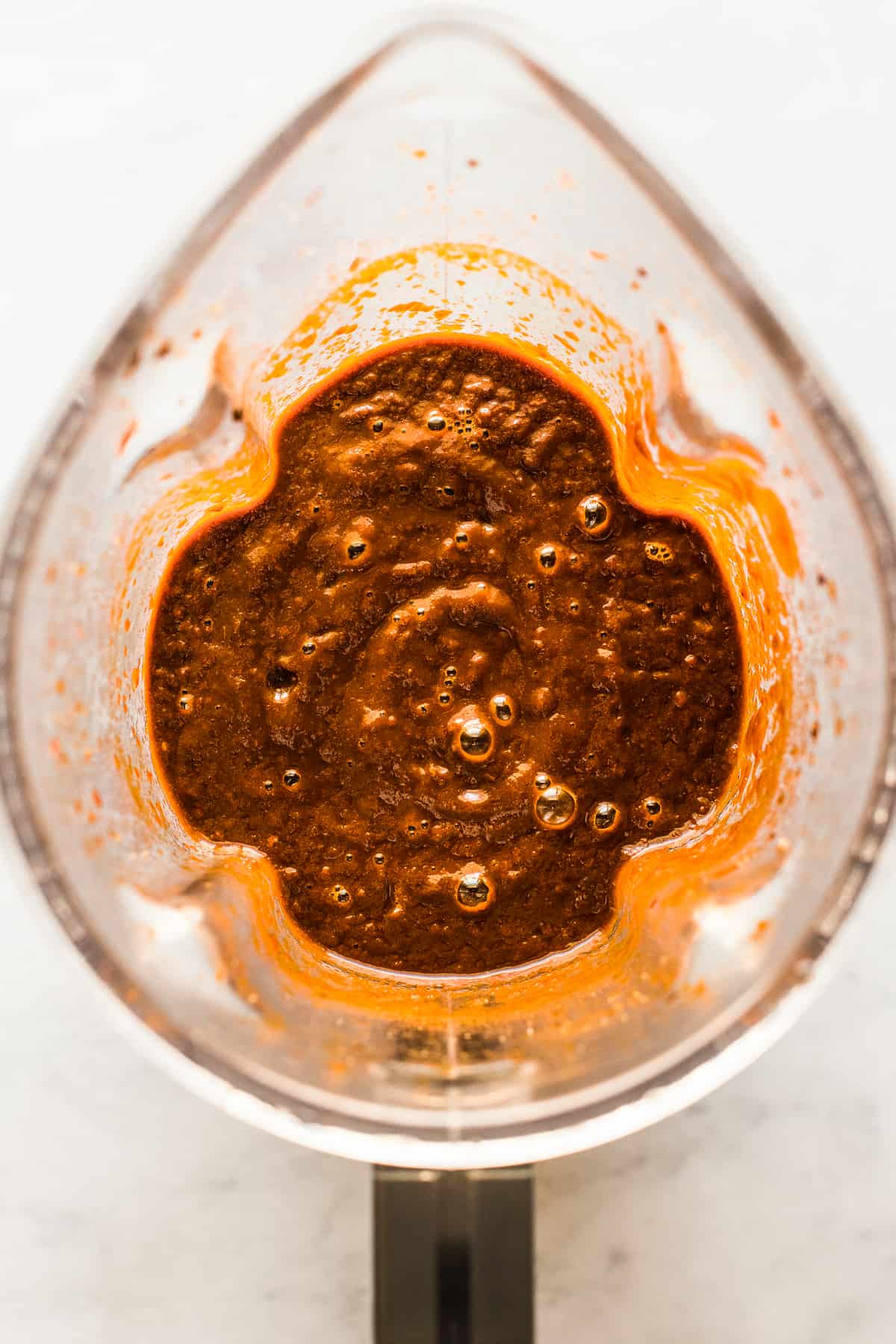A blended red chile sauce in a blender for tamales.