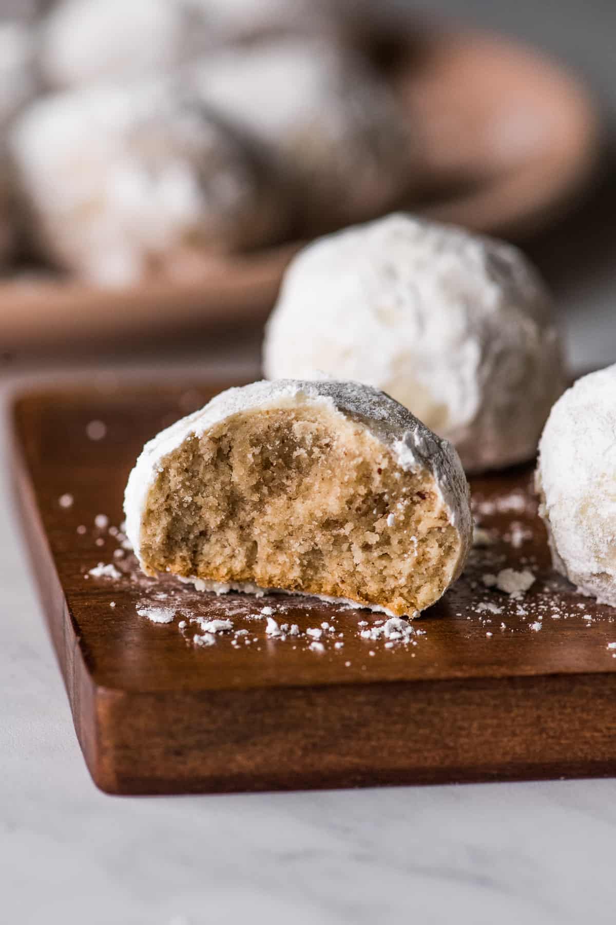 A Mexican wedding cookie with a bite taken out to show the buttery and crumbly interior.