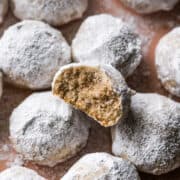 Mexican Wedding Cookies on a plate with one cookie with a bite taken out.