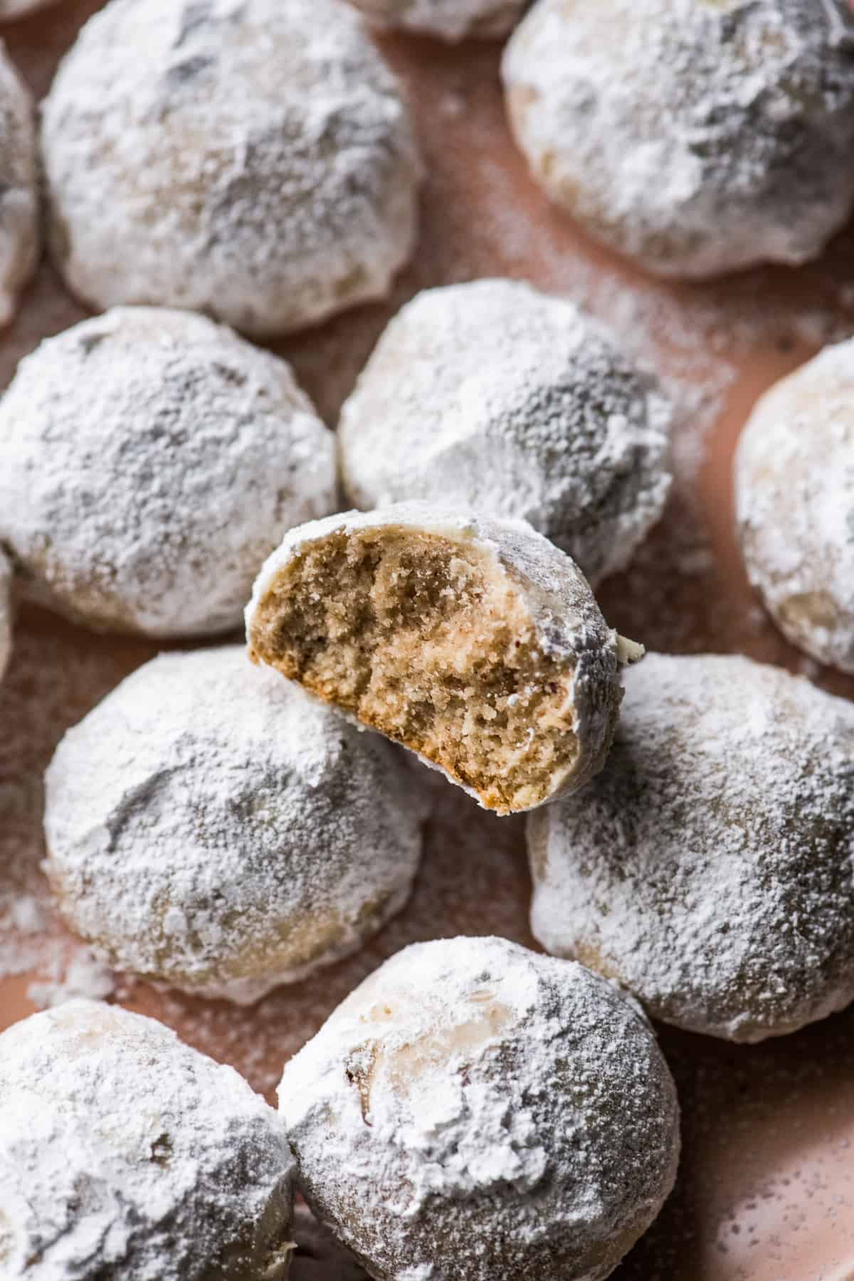 Mexican Wedding Cookies on a plate with one cookie with a bite taken out.