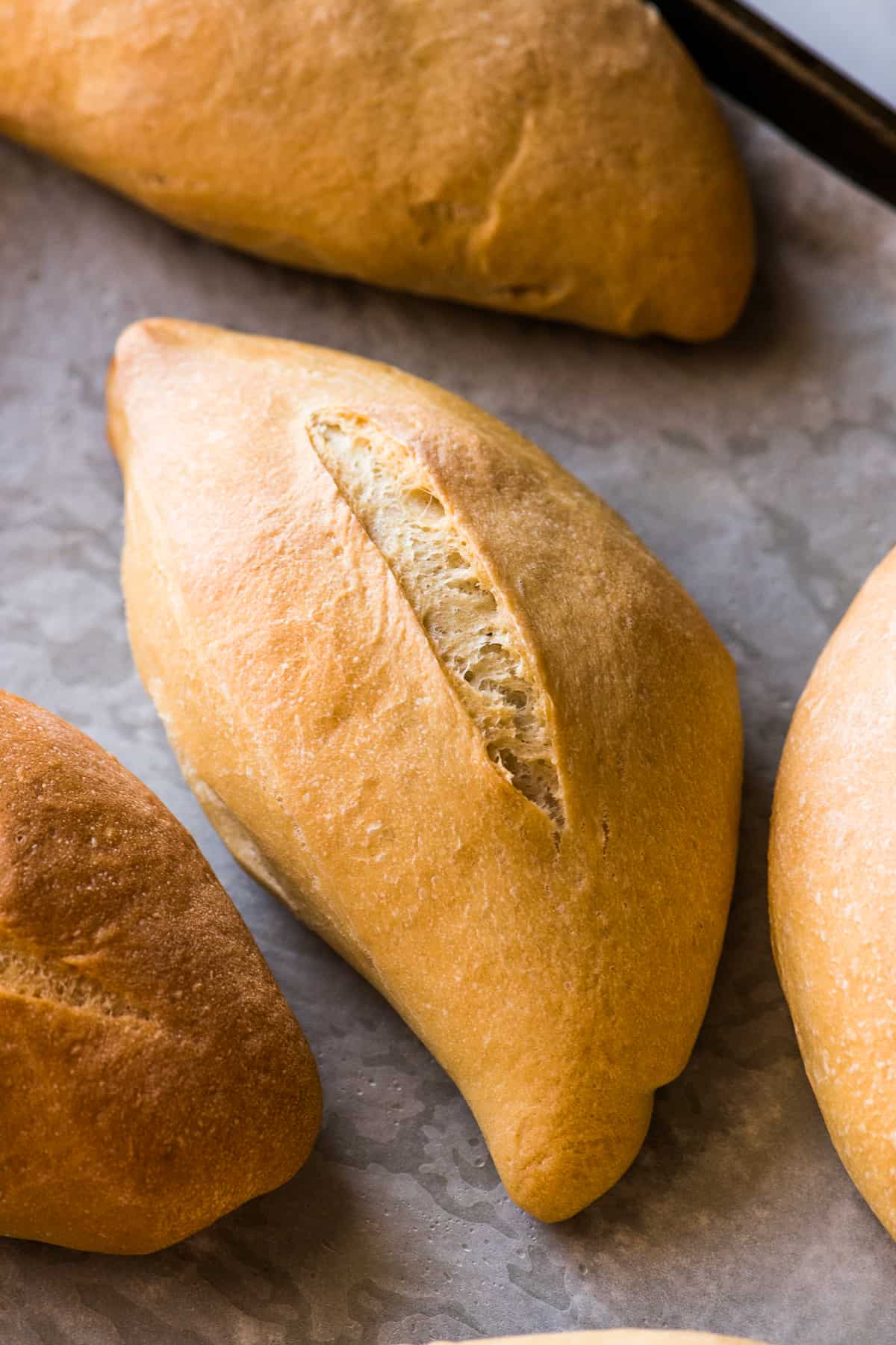 Baked bolillo with a golden brown crust on a baking sheet ready to eat.