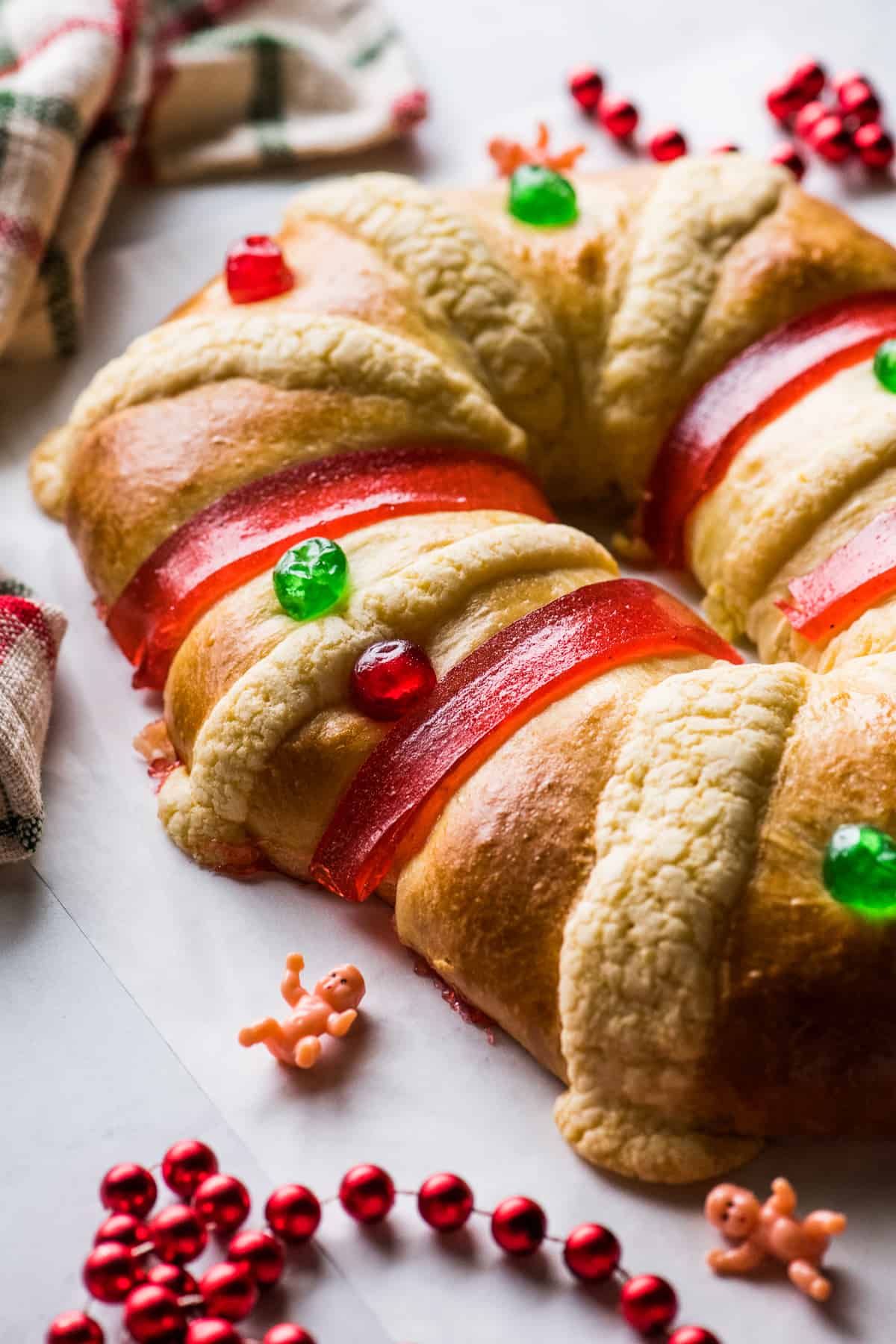 Rosca de Reyes, or Three Kings Bread, on a table next to a small baby Jesus figurine.