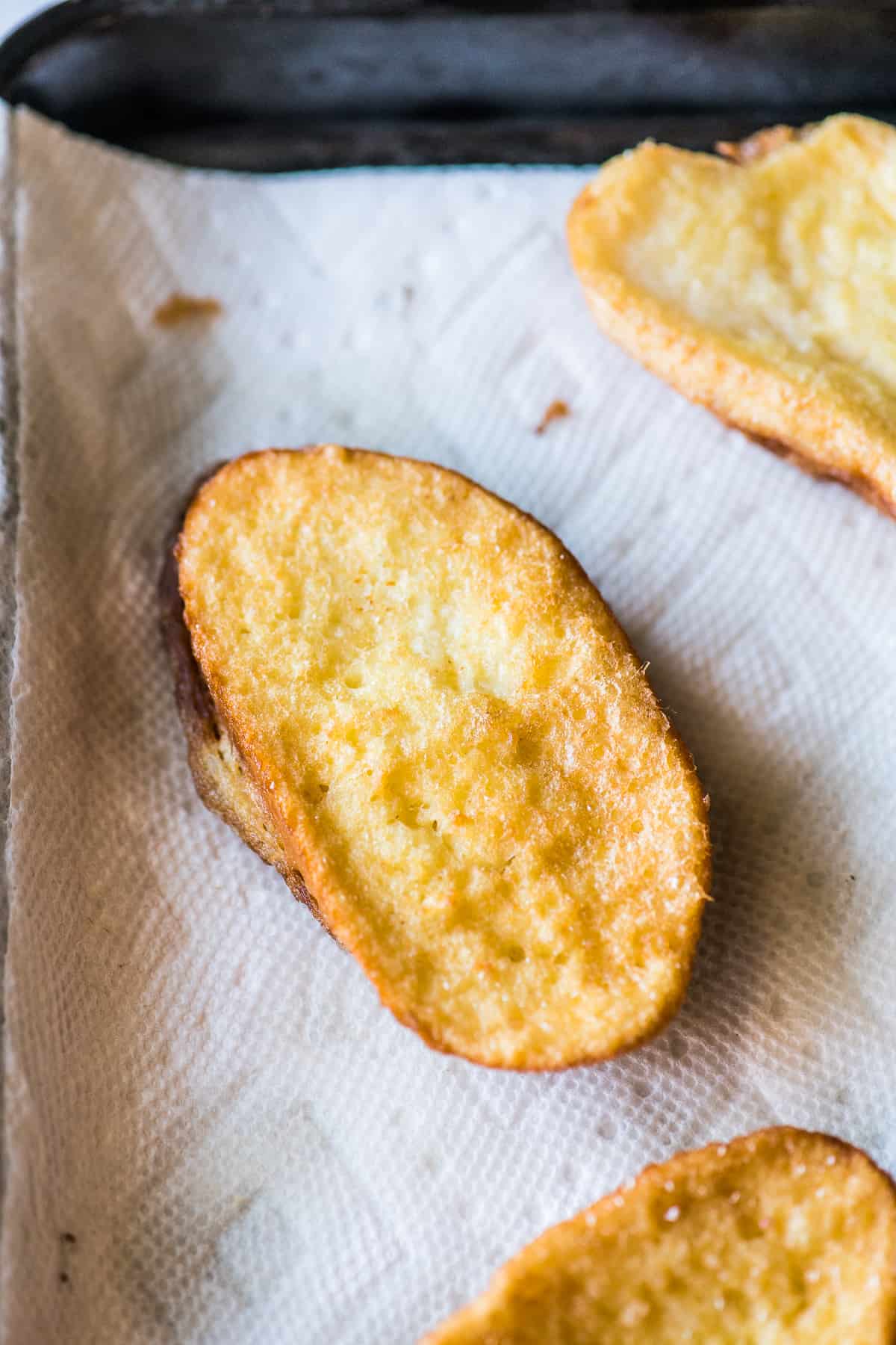 Fried torrejas on a baking sheet lined with paper towels used to remove any excess oil.