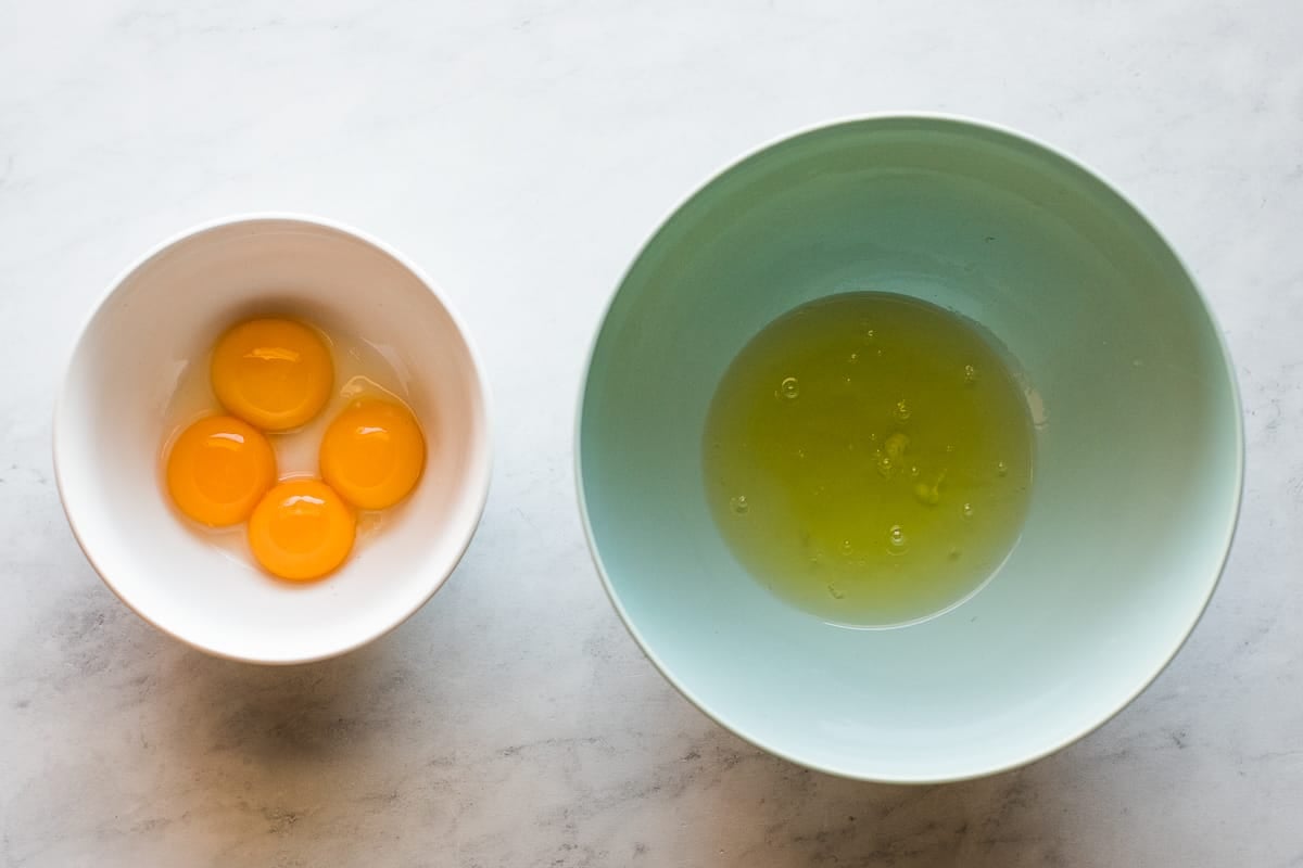 Las claras de huevo en un tazón grande y las yemas de huevo en un tazón pequeño separado.