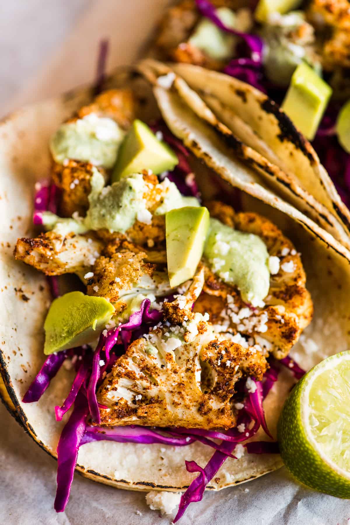 Cauliflower tacos topped with avocado, thinly sliced red cabbage, and queso fresco.