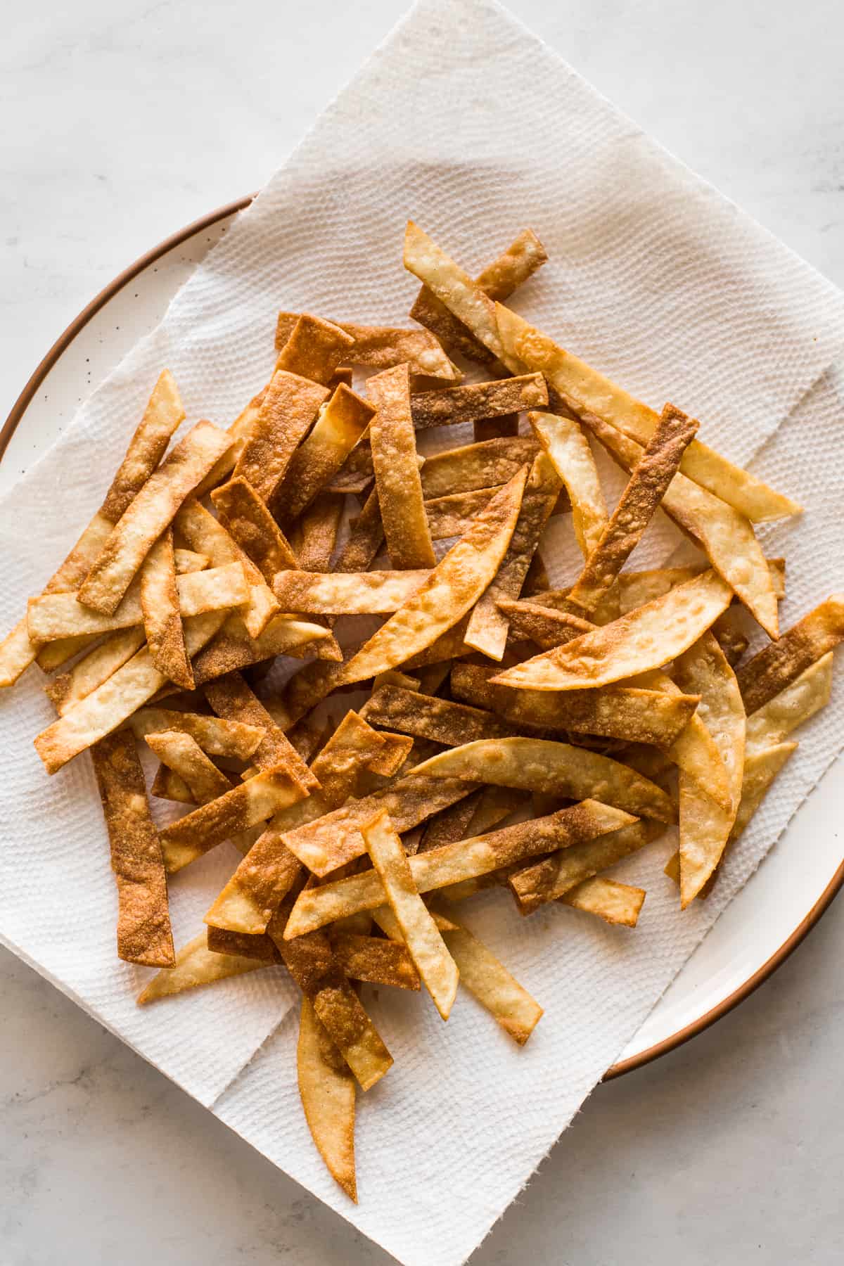 Fried tortilla strips on a plate for topping chicken tortilla soup.