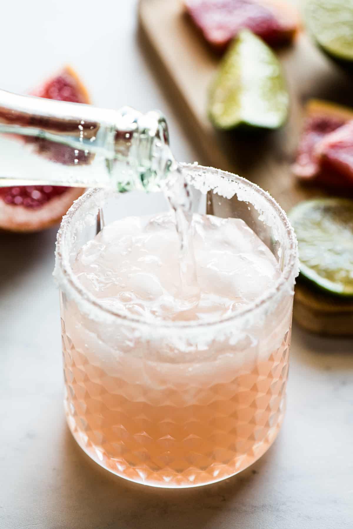 Sparkling water being poured into a paloma cocktail.