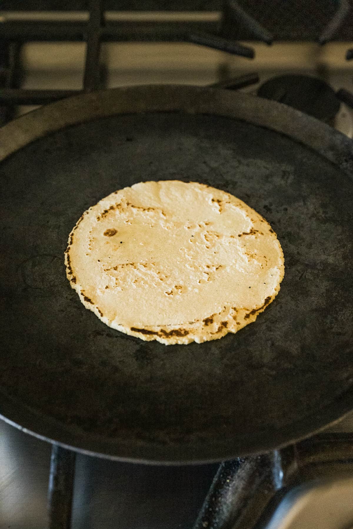 A cooked corn tortilla on a comal.