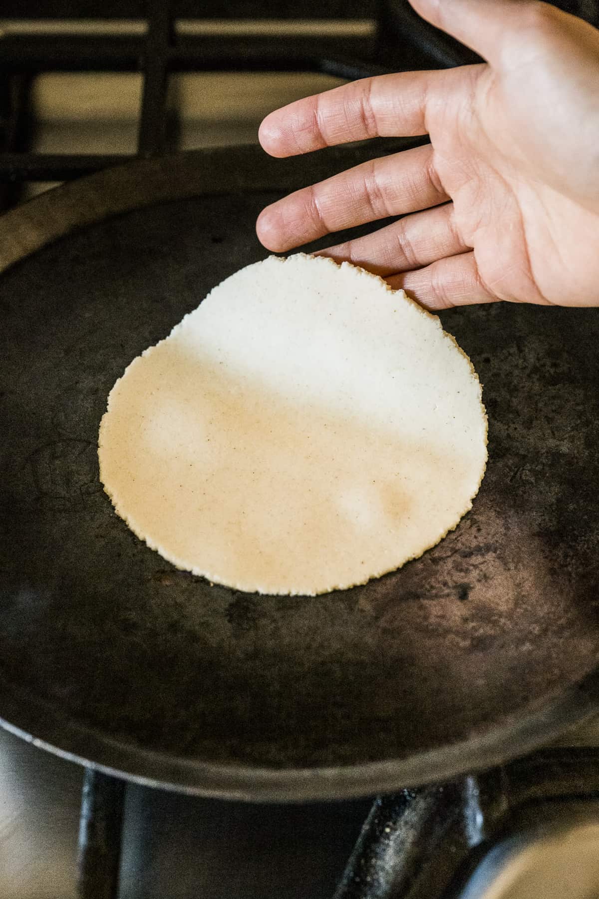 A corn tortilla being cooked on a comal.