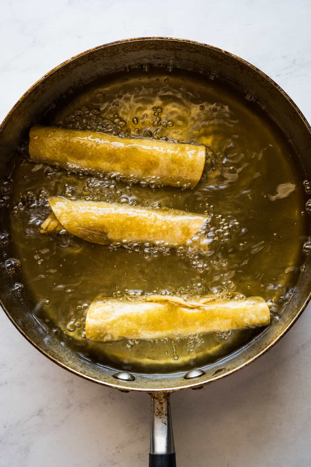 Flautas being fried in oil.