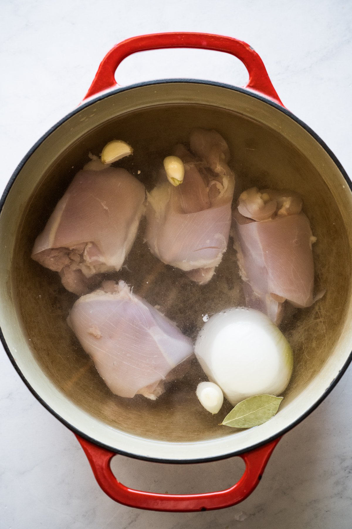 Chicken thighs cooking in a Dutch oven.