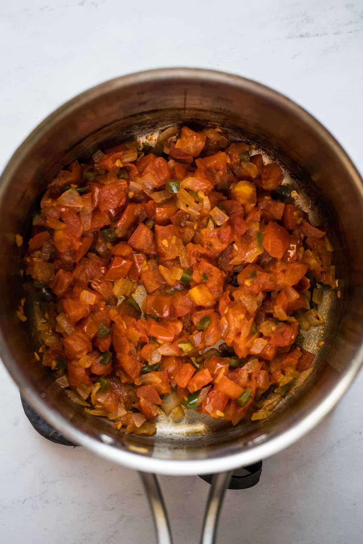 Diced tomatoes, onions, and jalapenos cooking in a small pot.