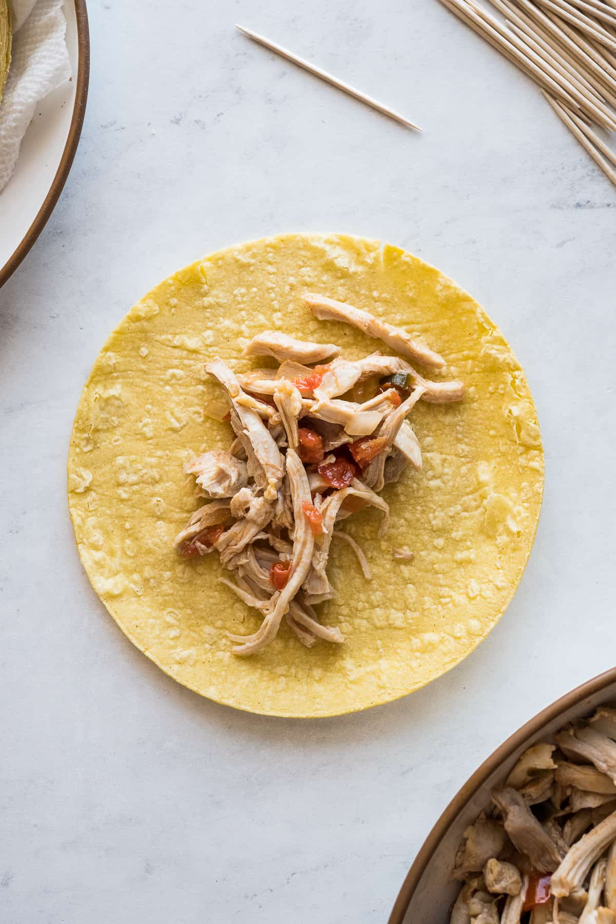 Shredded chicken filling on a corn tortilla to make a flauta.