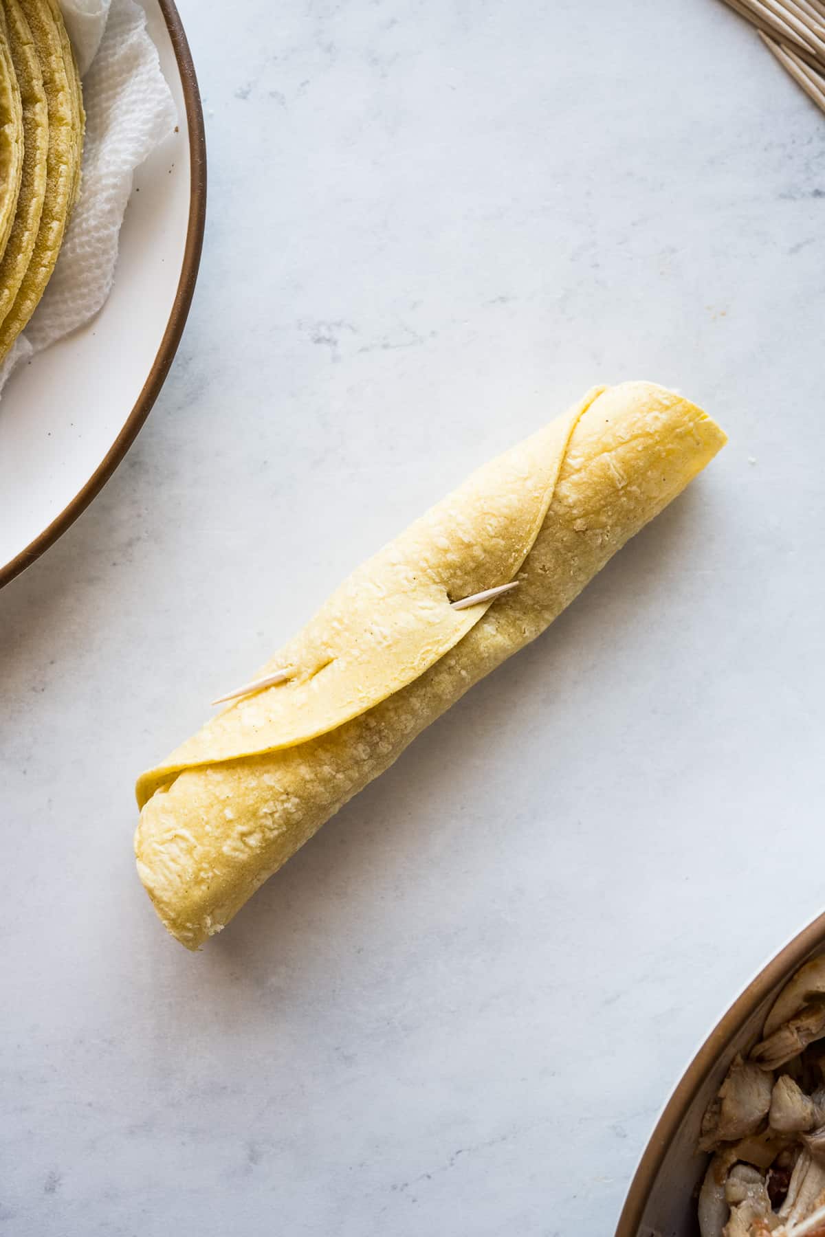 A flauta secured with a toothpick before frying.