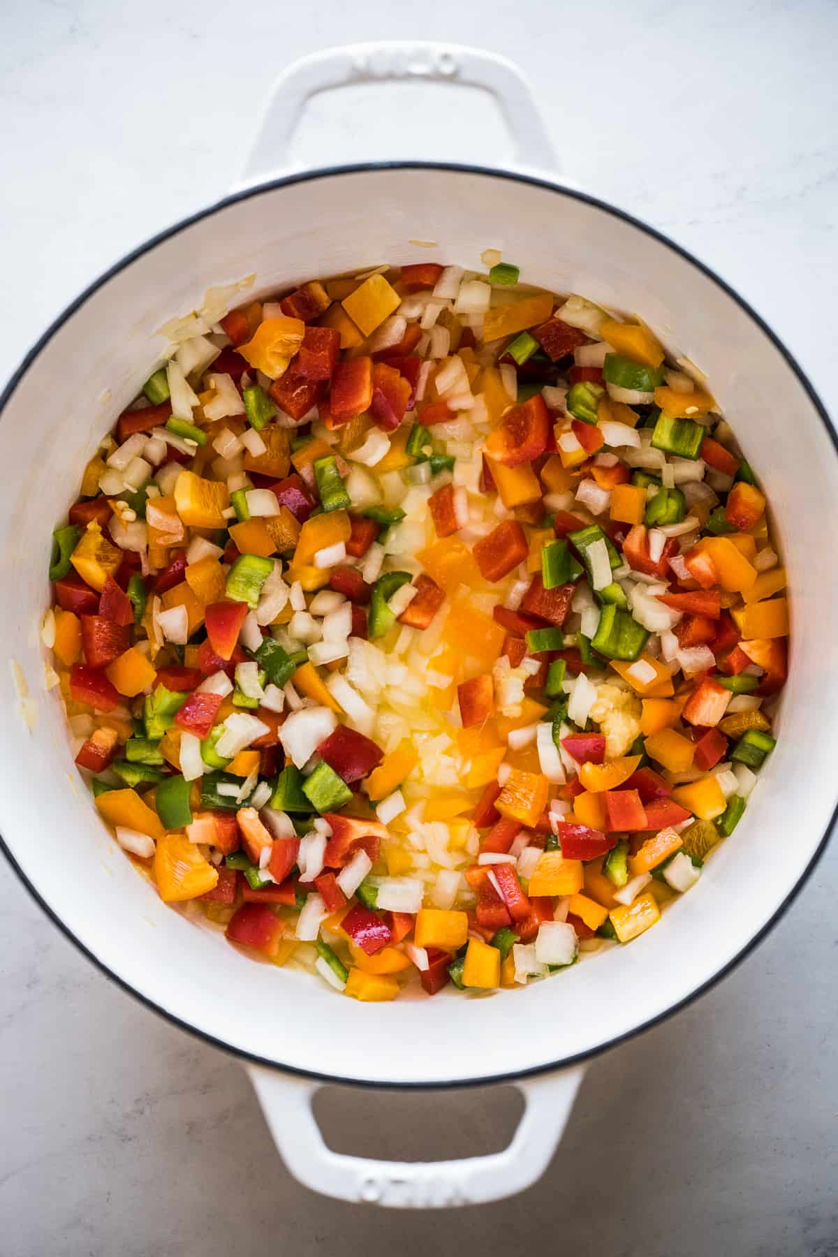 Peppers, onions, and garlic cooking in a pot.