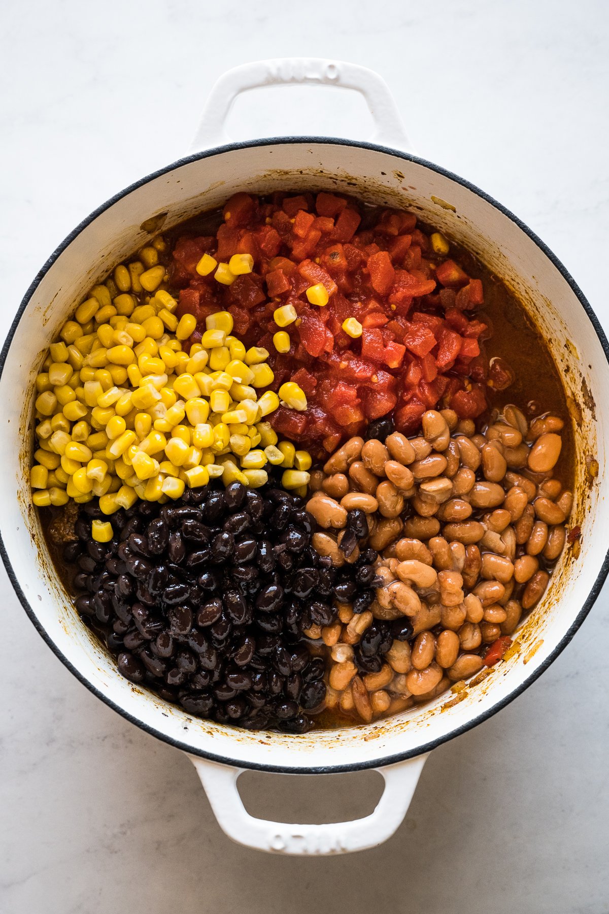 Corn, black beans, pinto beans, and diced tomatoes in a pot for taco soup.