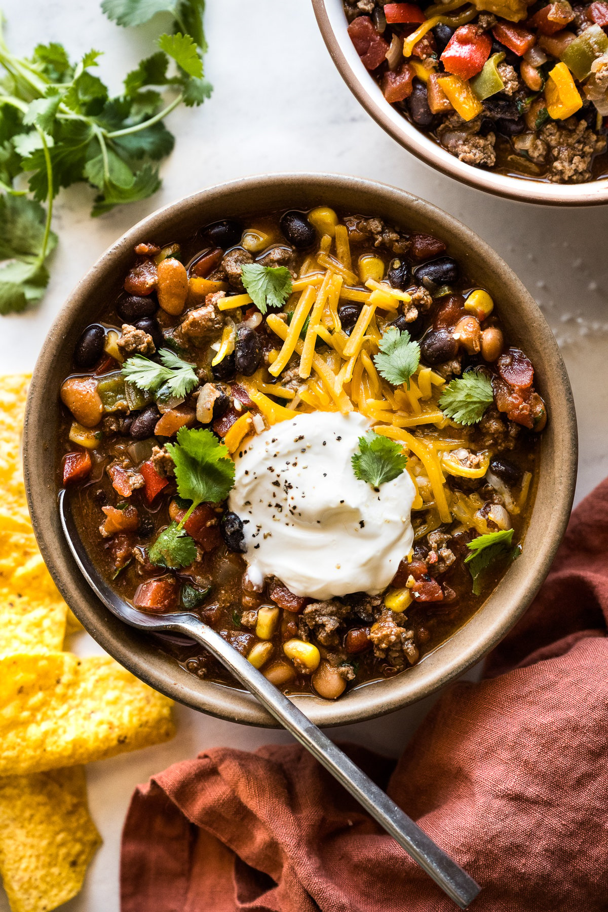 Taco soup in a bowl topped with shredded cheese, sour cream, and cilantro.