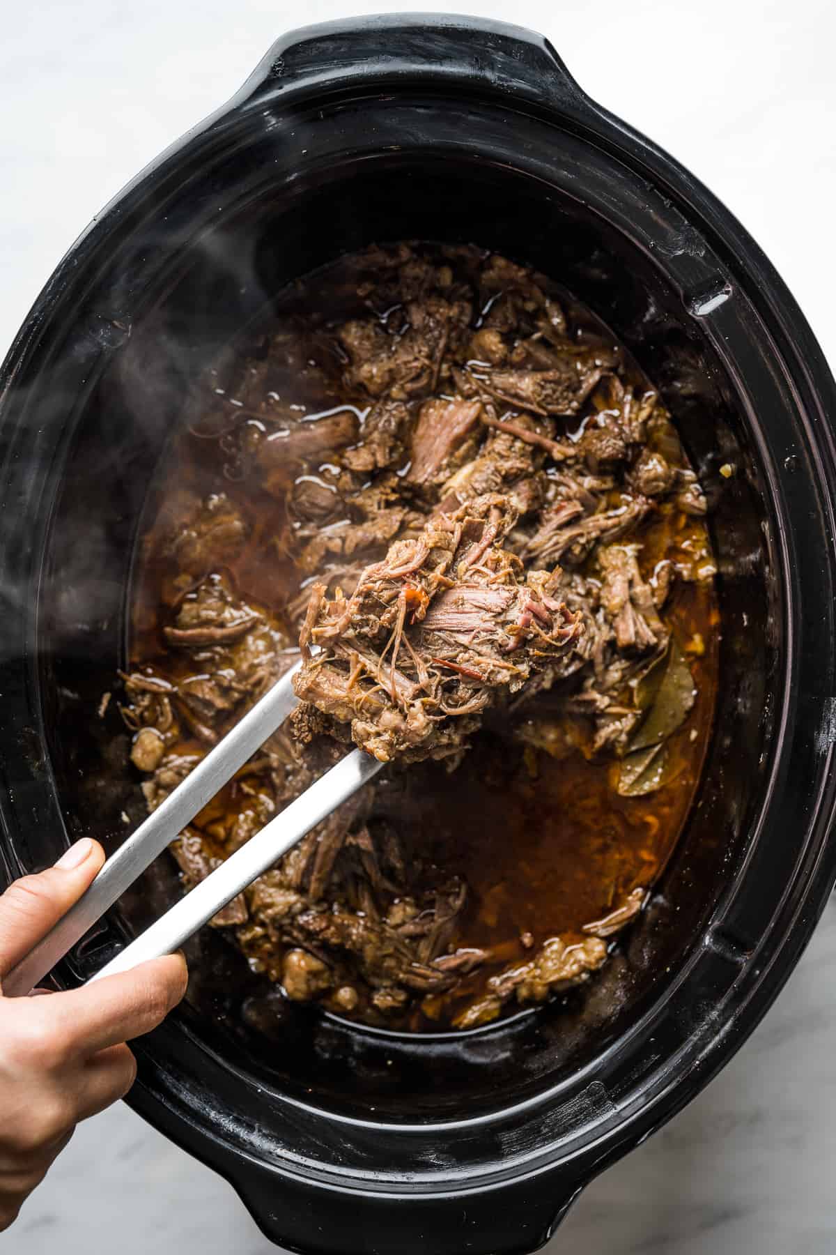 Shredded beef placed back into slow cooker to soak up juices for ten minutes. 