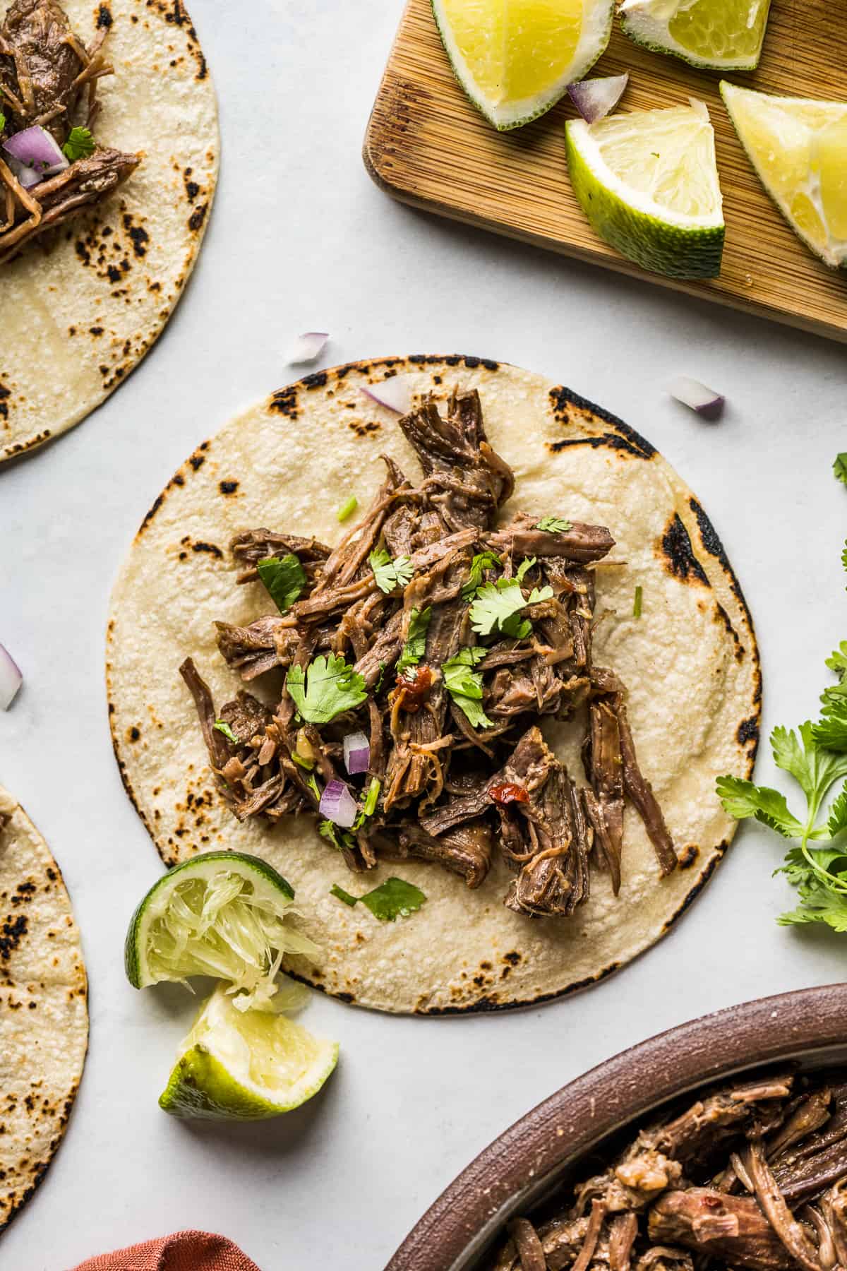 Fully cooked barbacoa placed in a corn tortilla with cilantro and lime juice. 