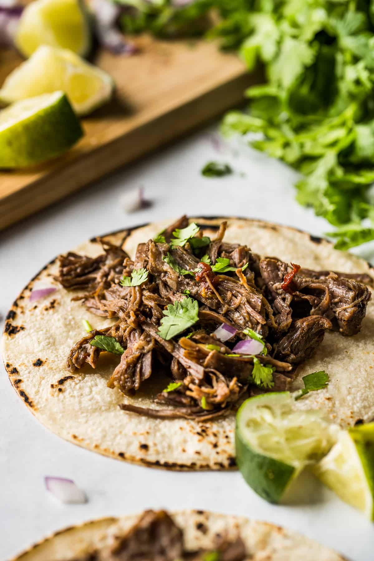 Corn tortilla filled with barbacoa meat topped with lime juice, red onions, and cilantro. 