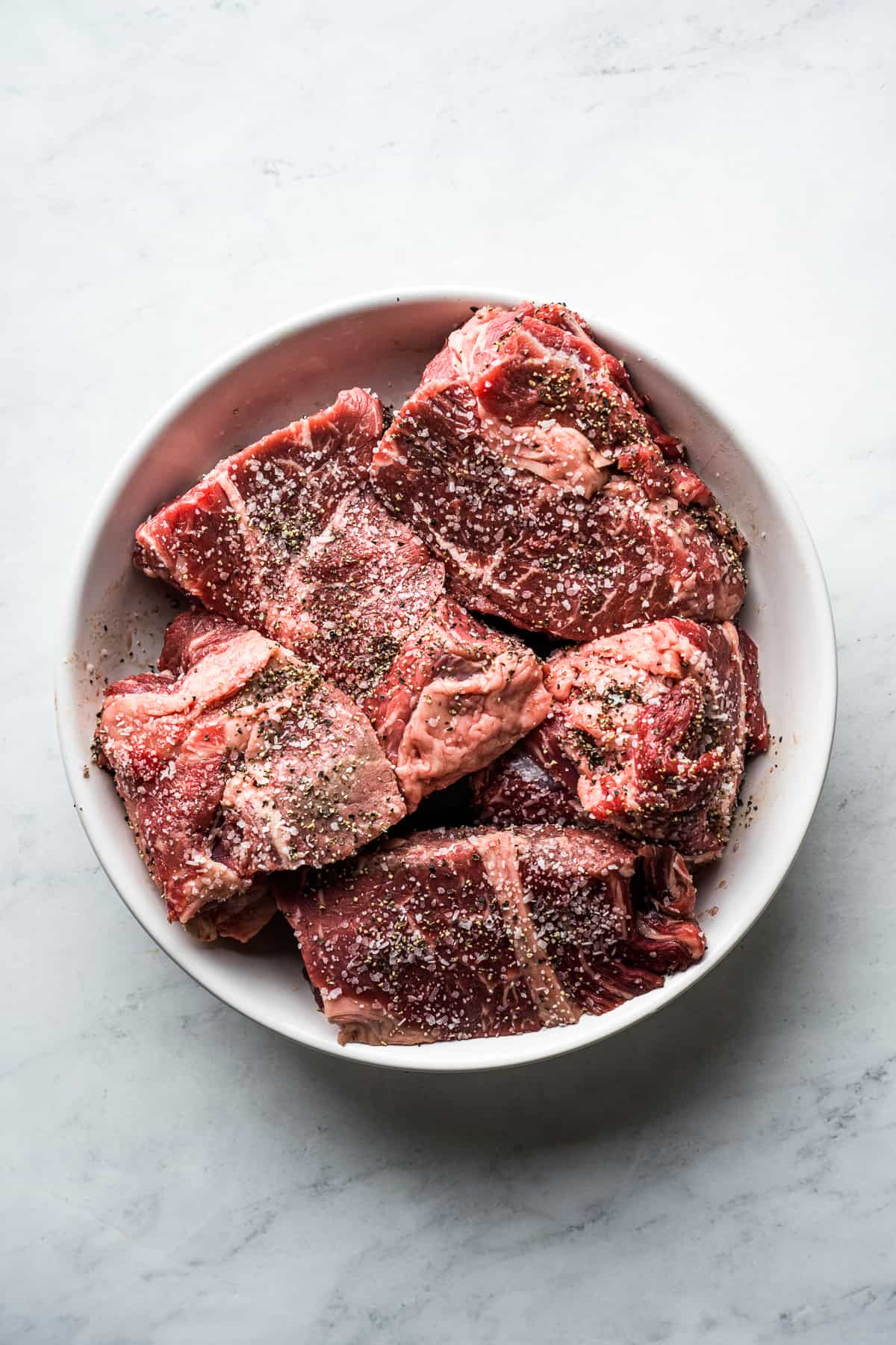 Beef cut into four inch pieces and seasoned in a mixing bowl. 