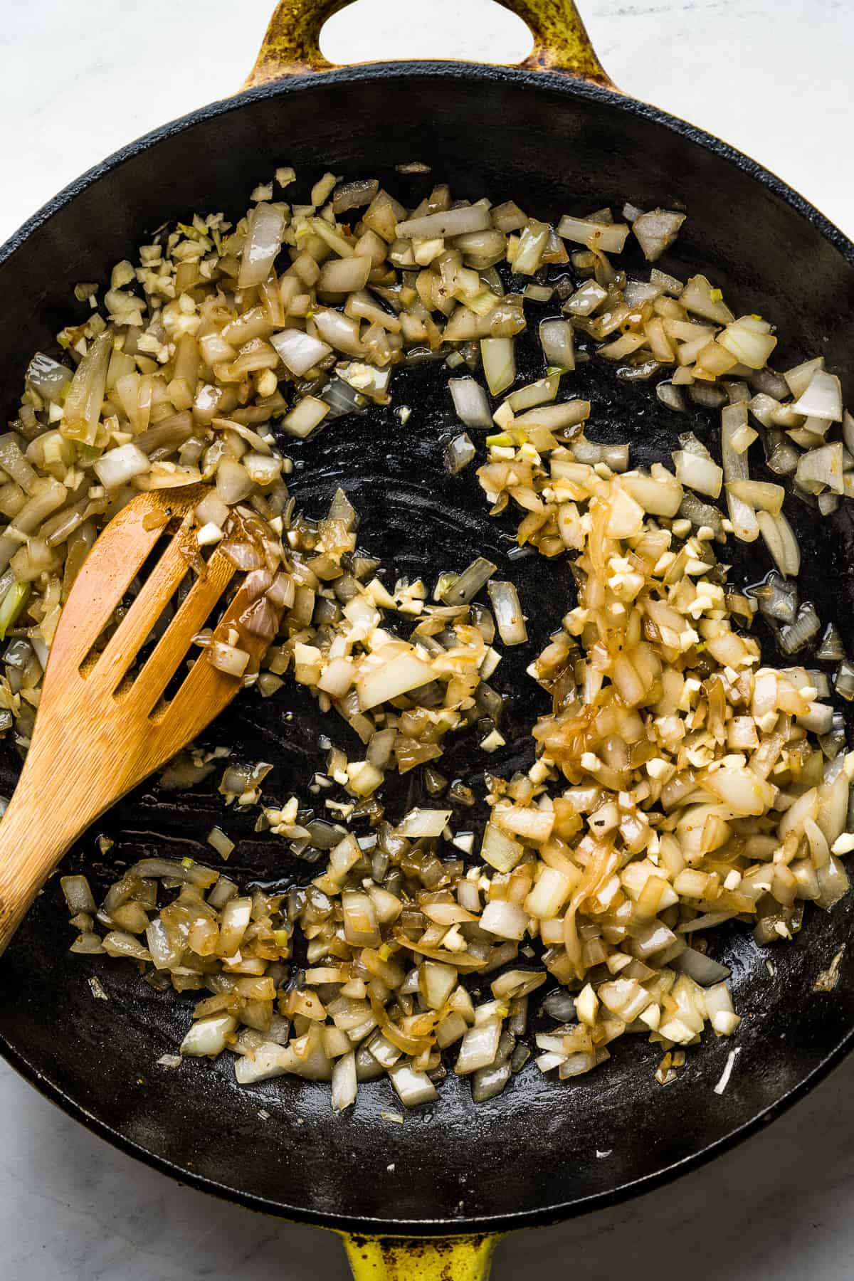Onions being cooked with garlic in the same skillet. 