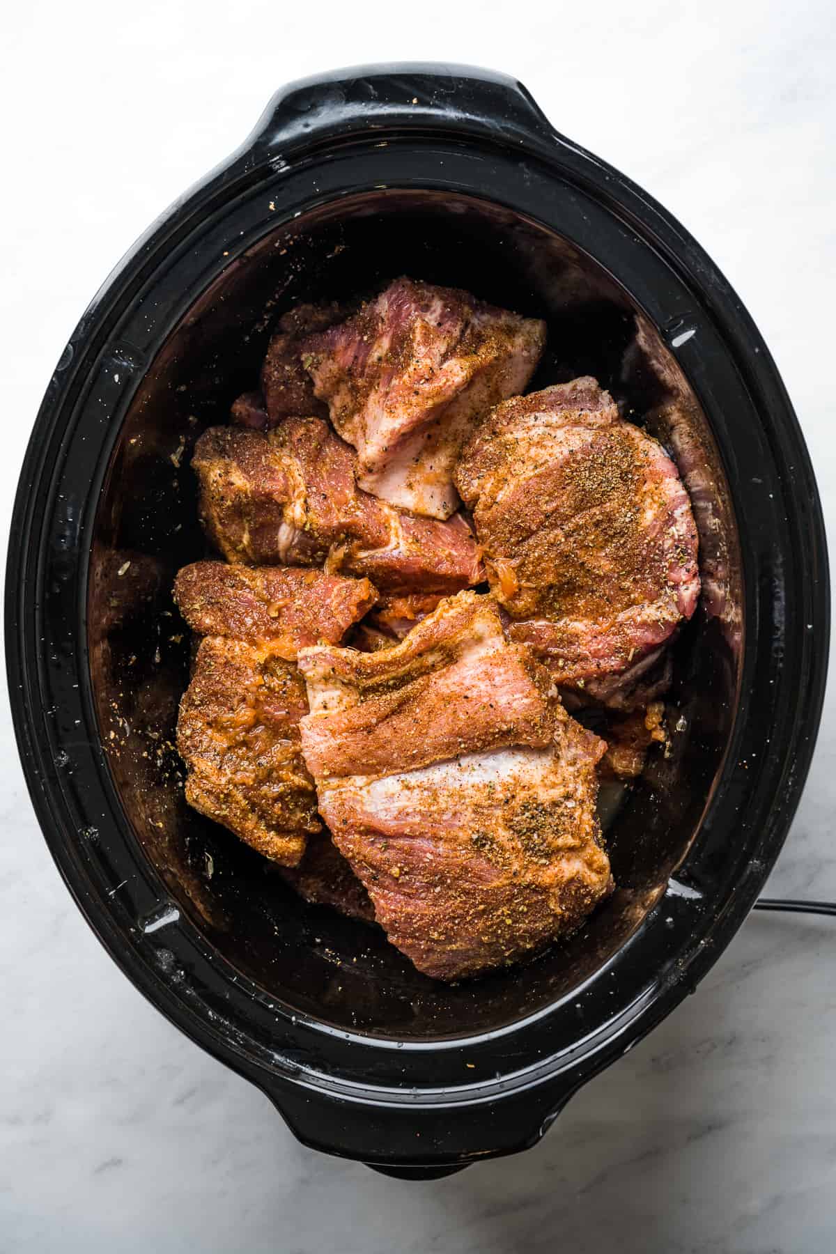 Seasoned pork shoulder, lime juice, and orange juice in a slow cooker.