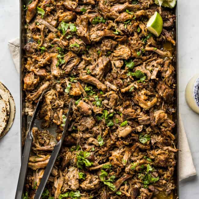 Authentic Carnitas on a sheet pan garnished with chopped cilantro.