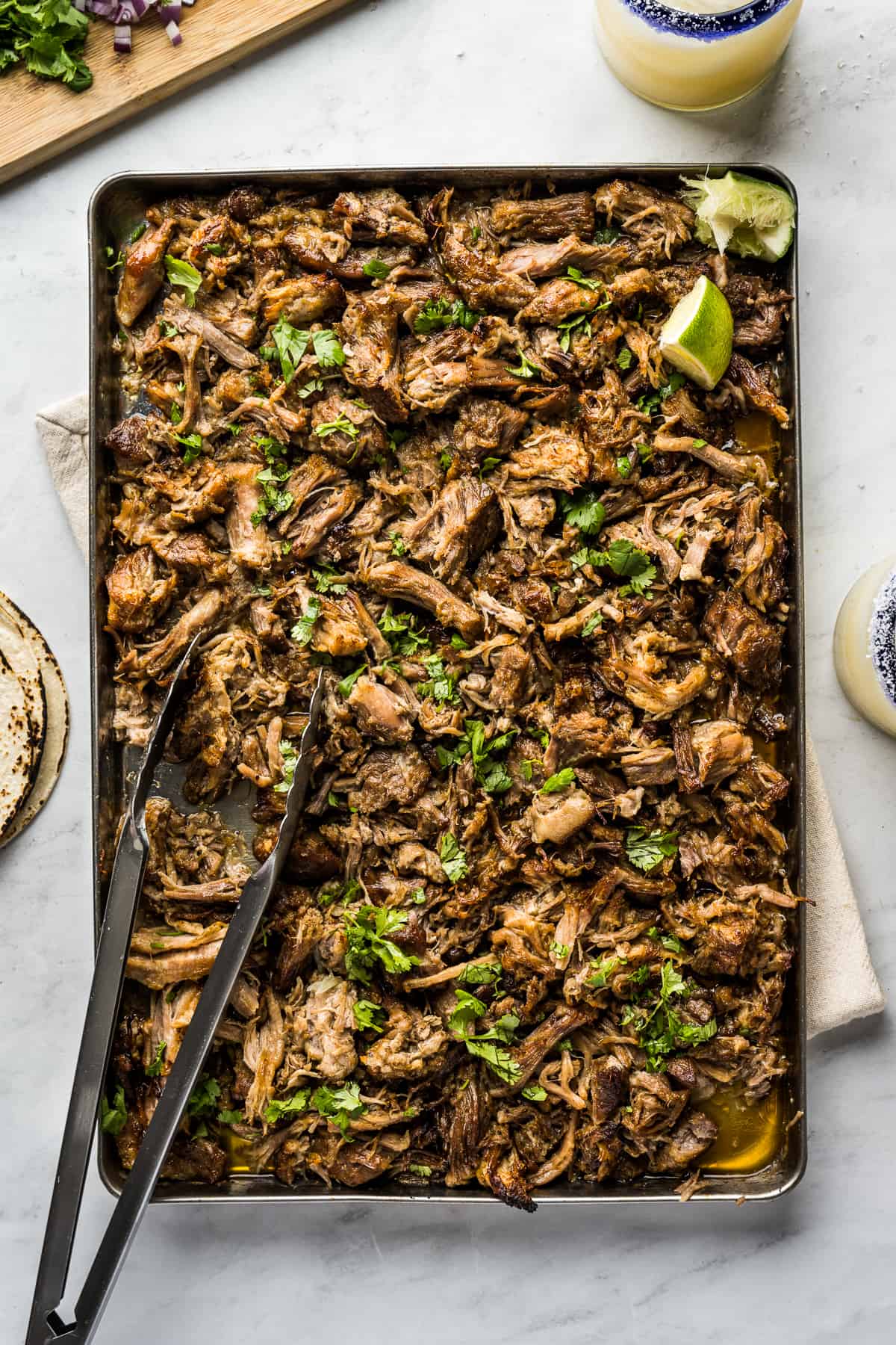 Authentic Carnitas on a sheet pan garnished with chopped cilantro.