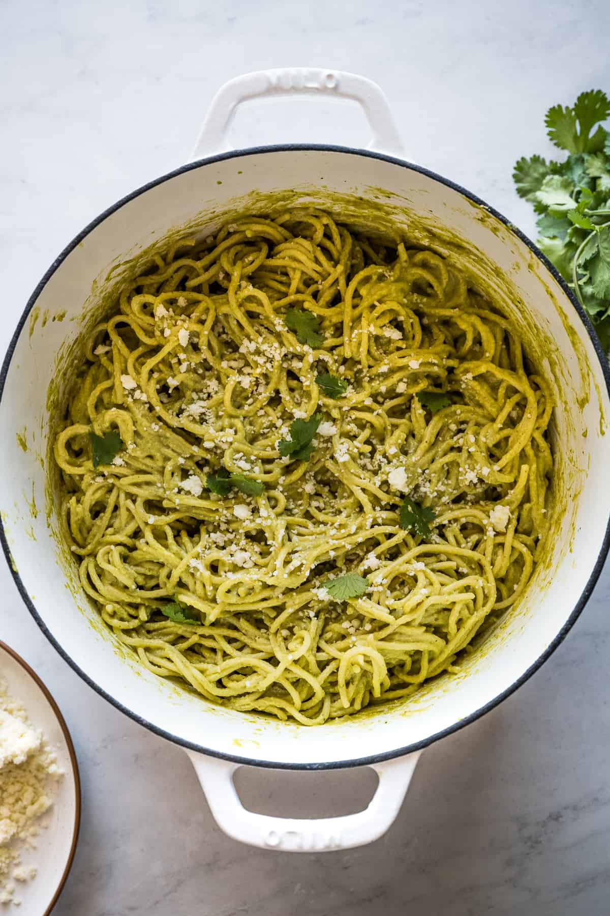 Green Spaghetti (Espagueti Verde) in a pot garnished with queso fresco and cilantro.