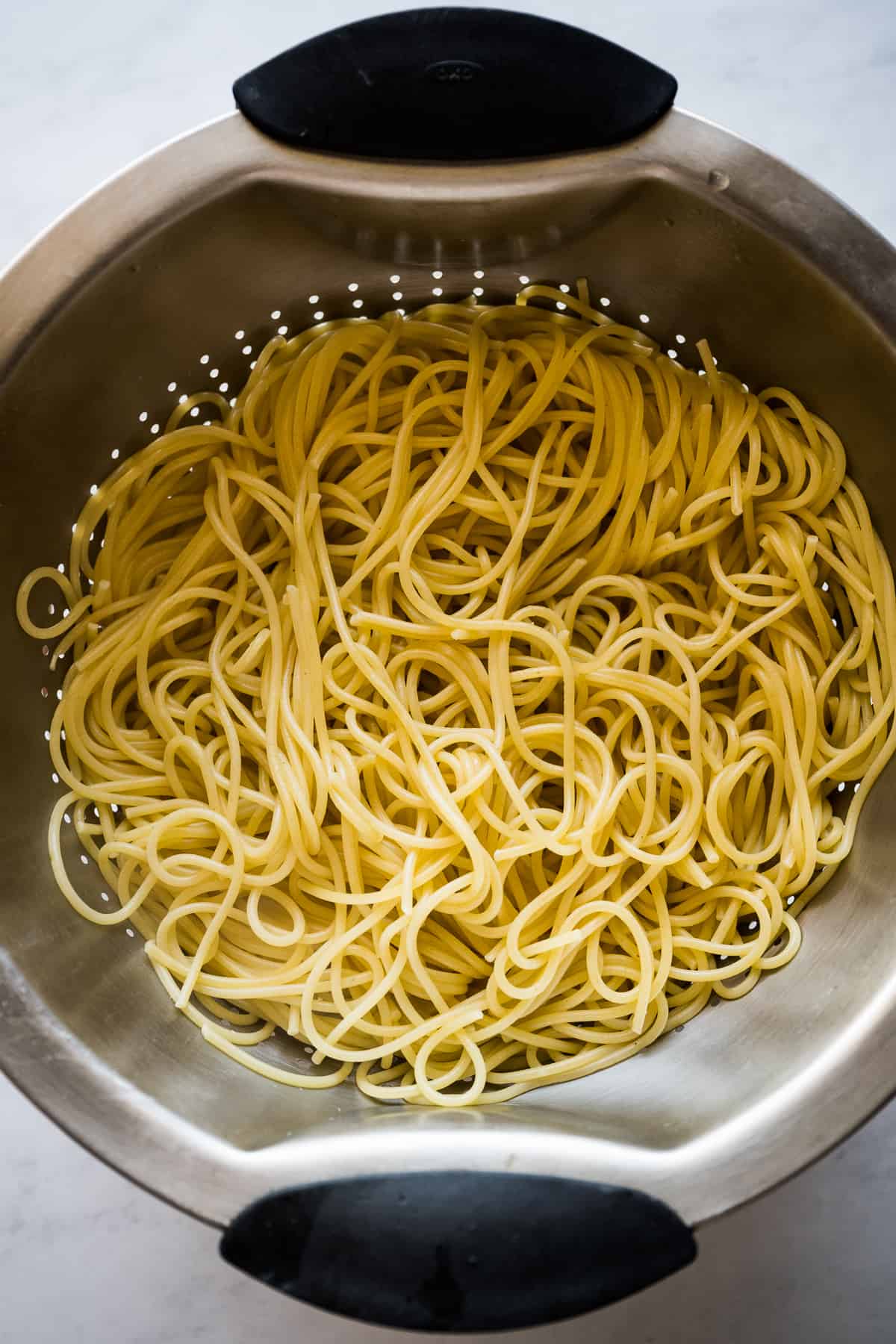 Cooked spaghetti noodles in a colander.