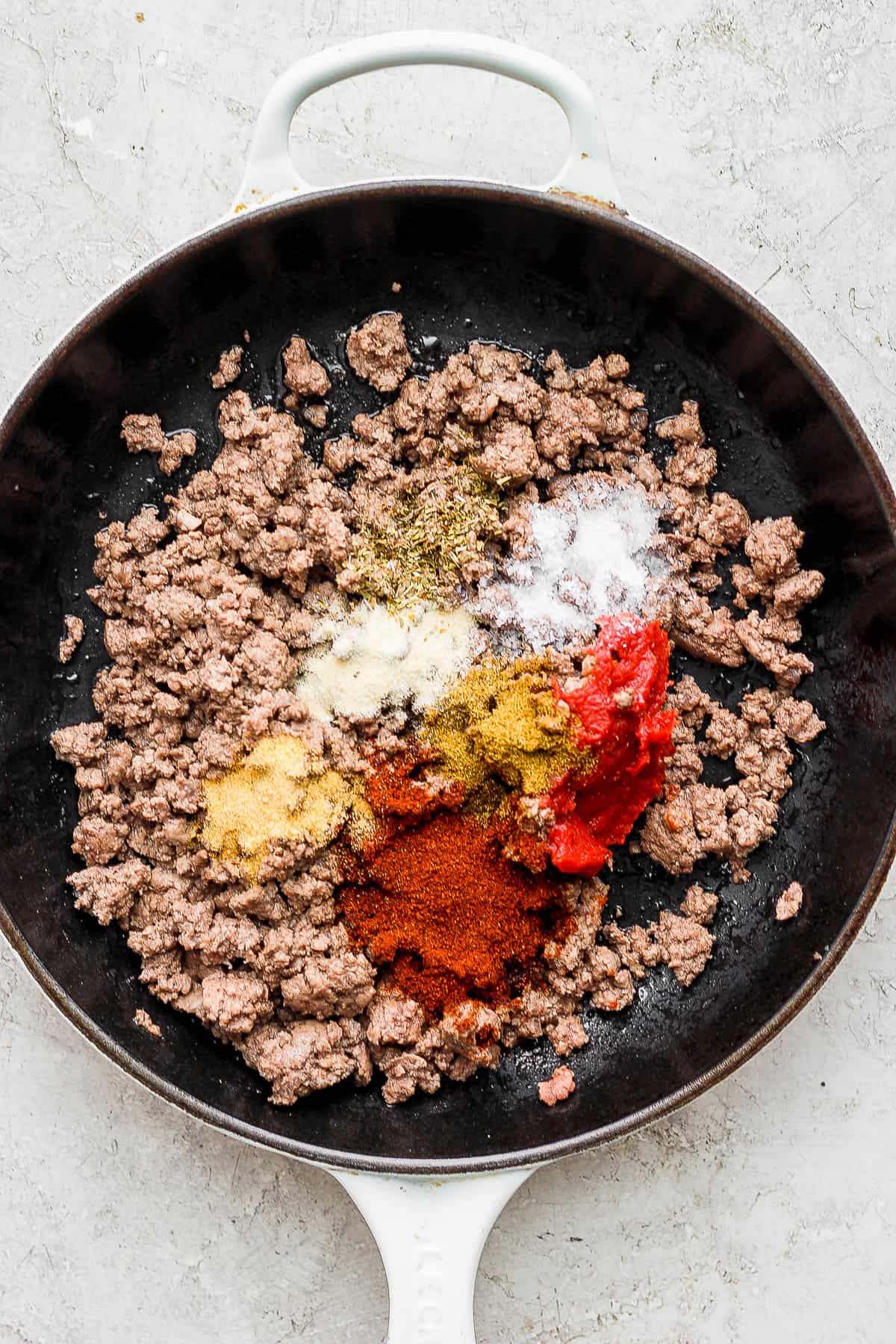 Ground beef and various seasonings in a skillet to make taco meat.