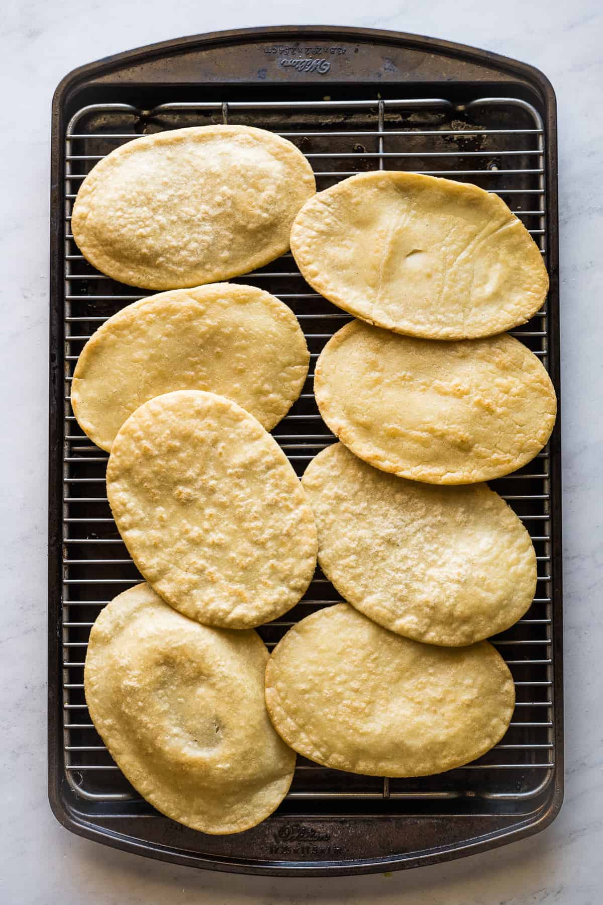 Fried huaraches on a baking sheet.