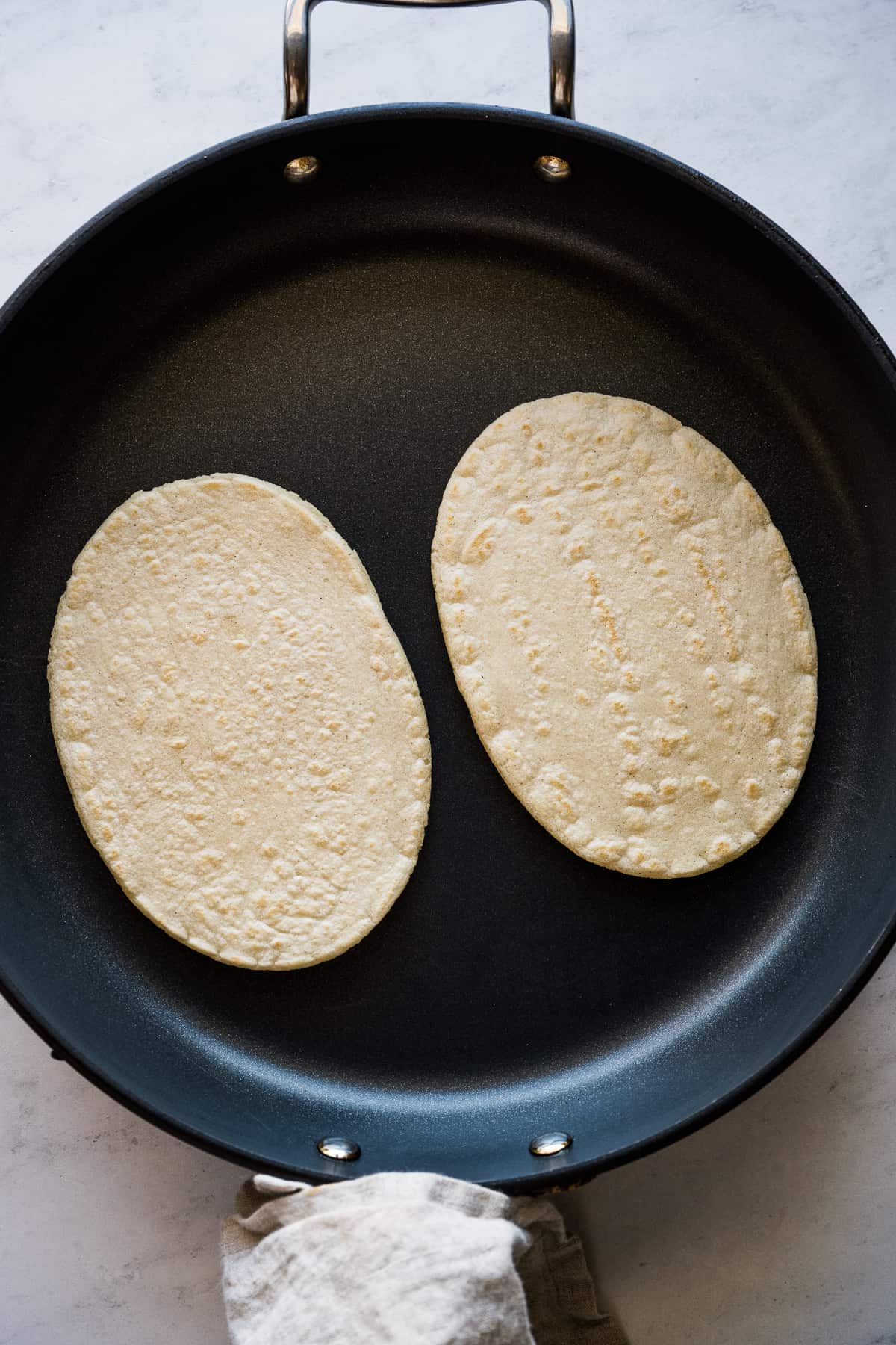 Huaraches being cooked in a skillet.