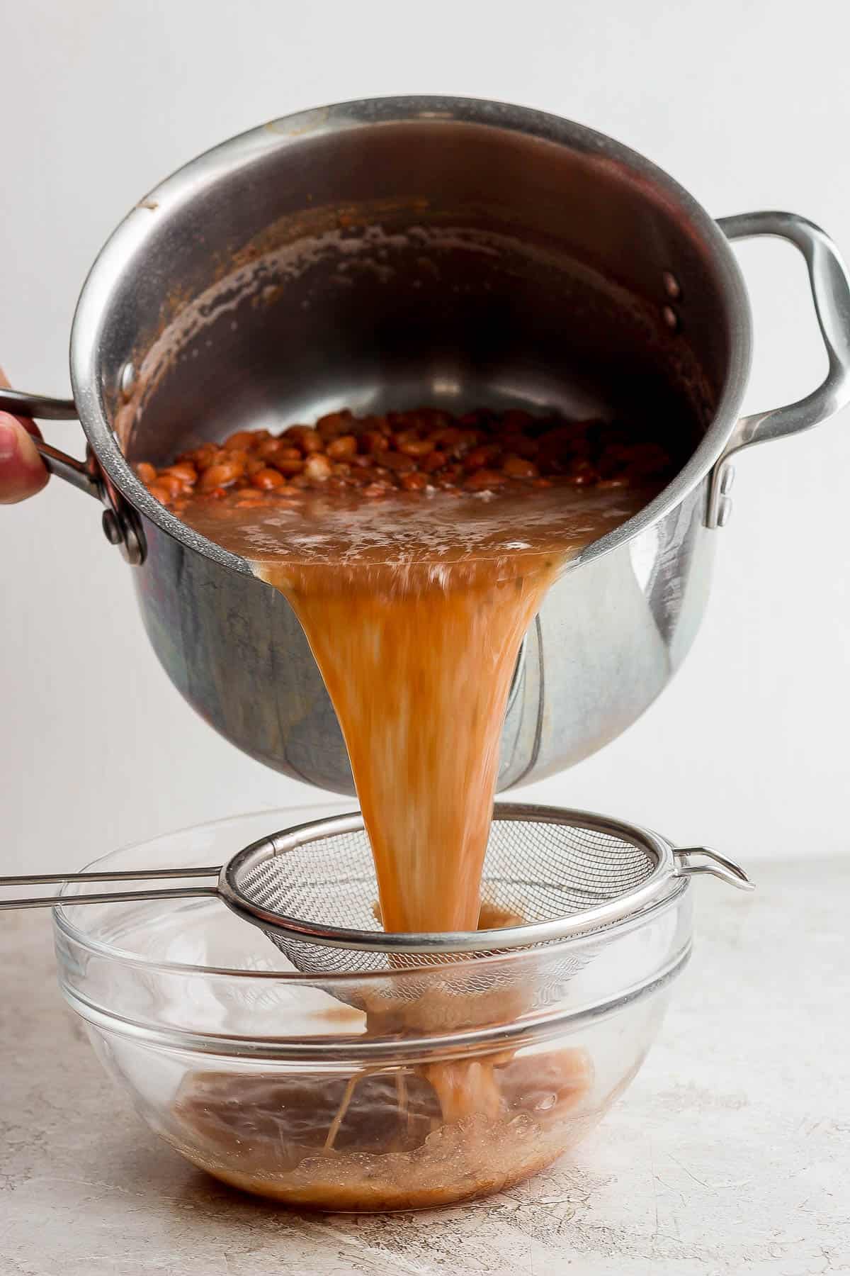 Cooked pinto beans being poured through a colander and into a bowl to save the bean cooking liquid.