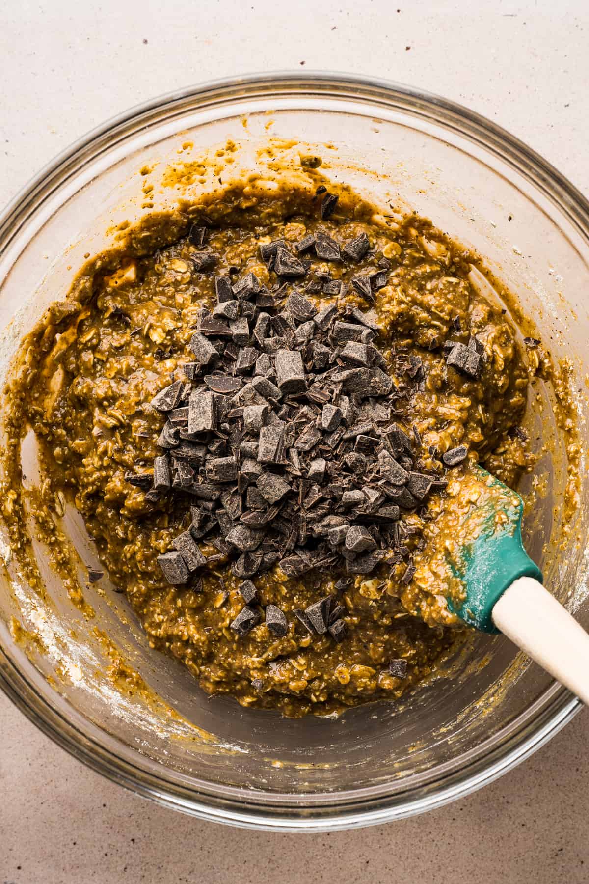 Chocolate chunks being mixed into a bowl for chocolate oat bars.