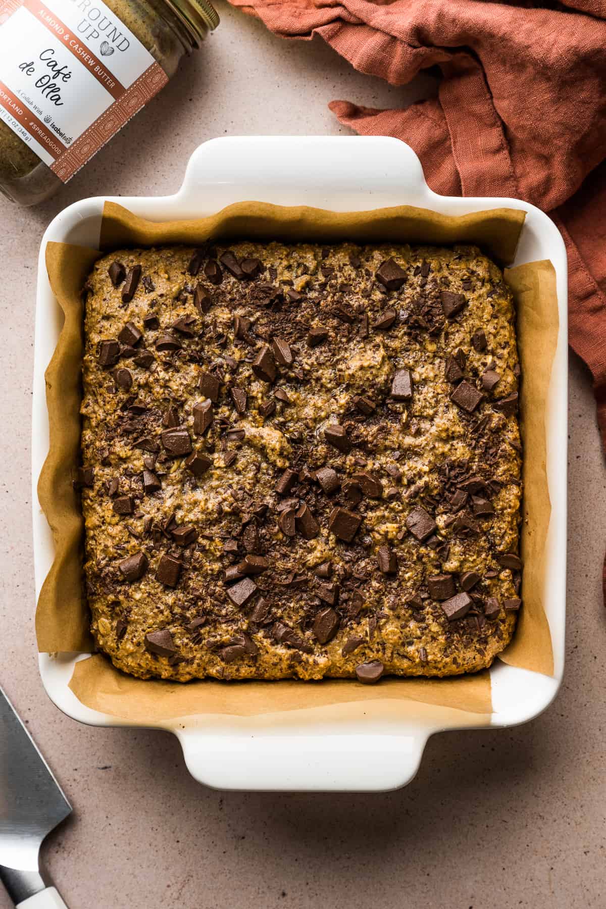 Chocolate oat bars topped with chocolate chunks in a baking dish.