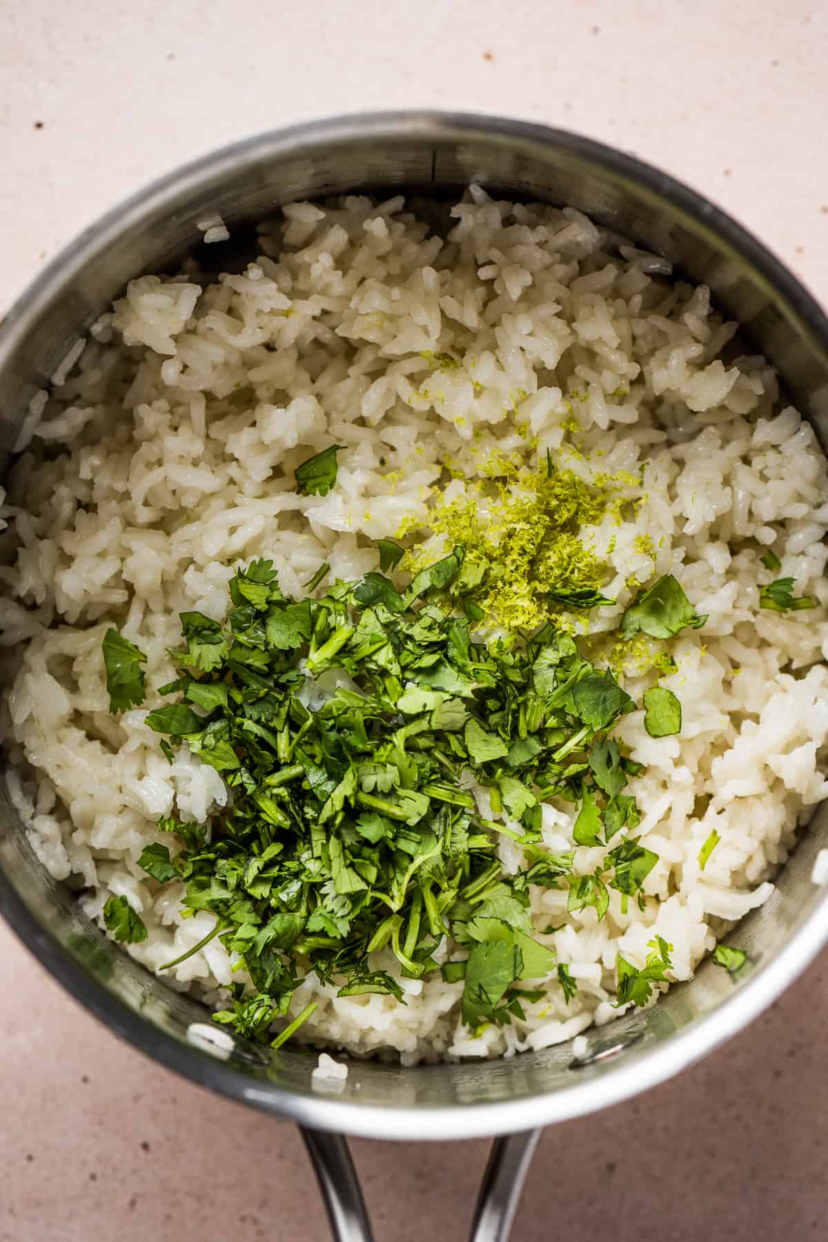 Cooked rice in a pot topped with cilantro, lime juice, and lime zest 