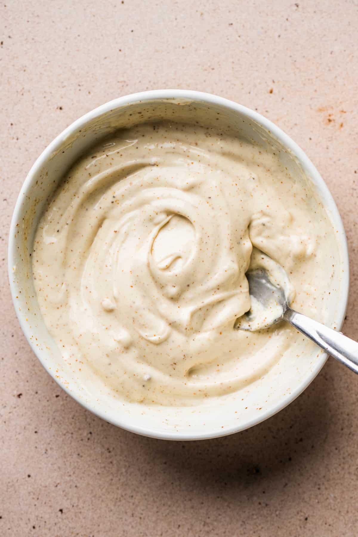 A bowl of creamy mayo sauce for topping elote.