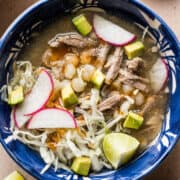 Pozole blanco in a bowl topped with avocado, radishes, and thinly sliced cabbage.